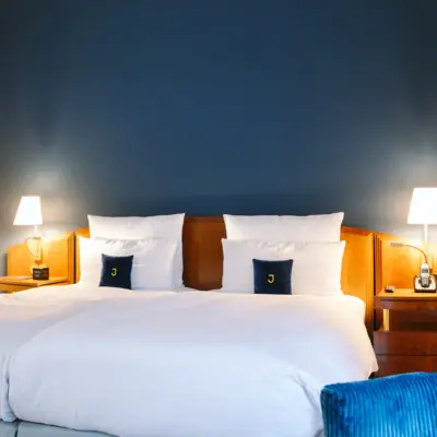 A bed in front of a blue wall in the Hotel Louis C. Jacob.