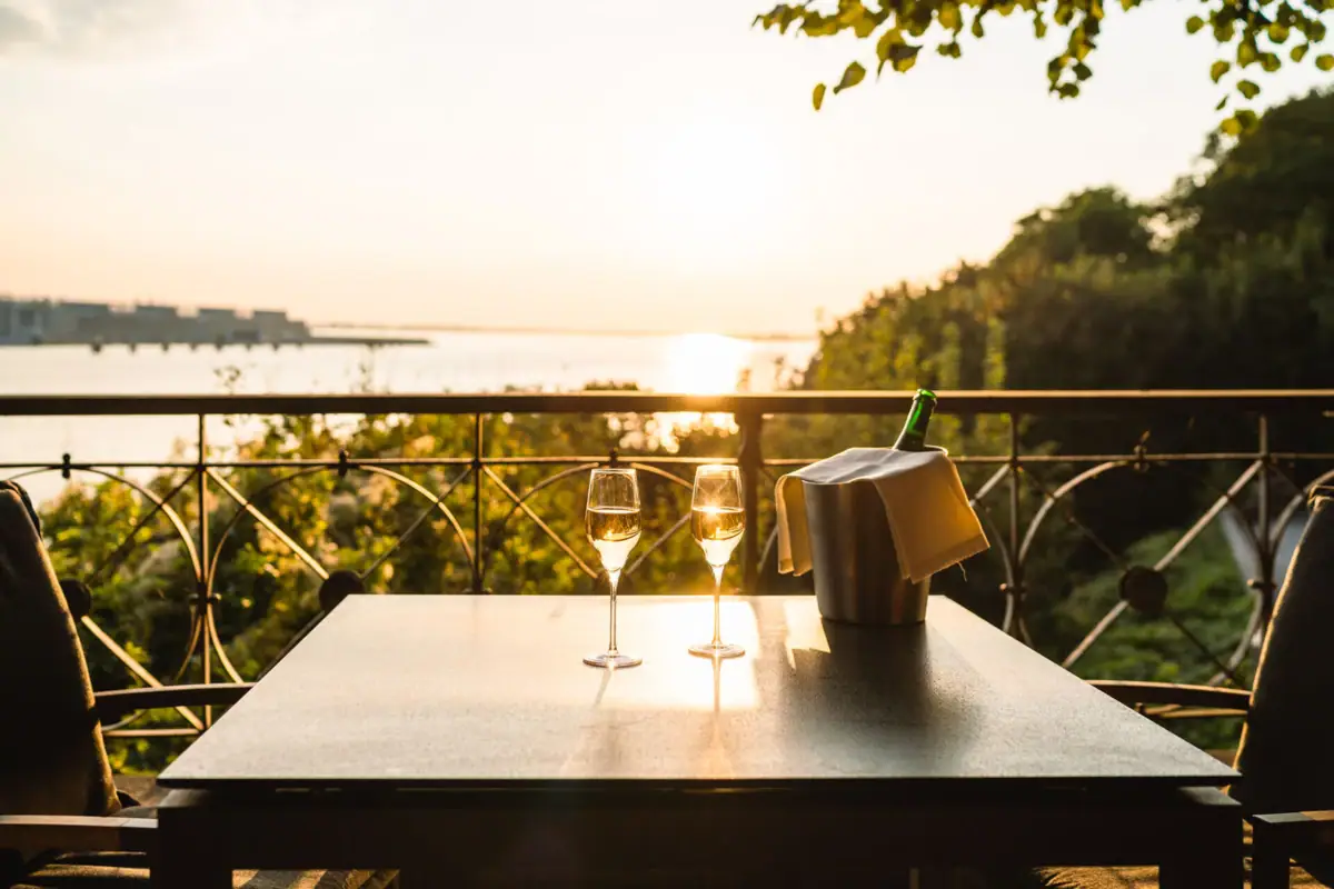 A table with wine glasses and a bucket of wine outdoors.