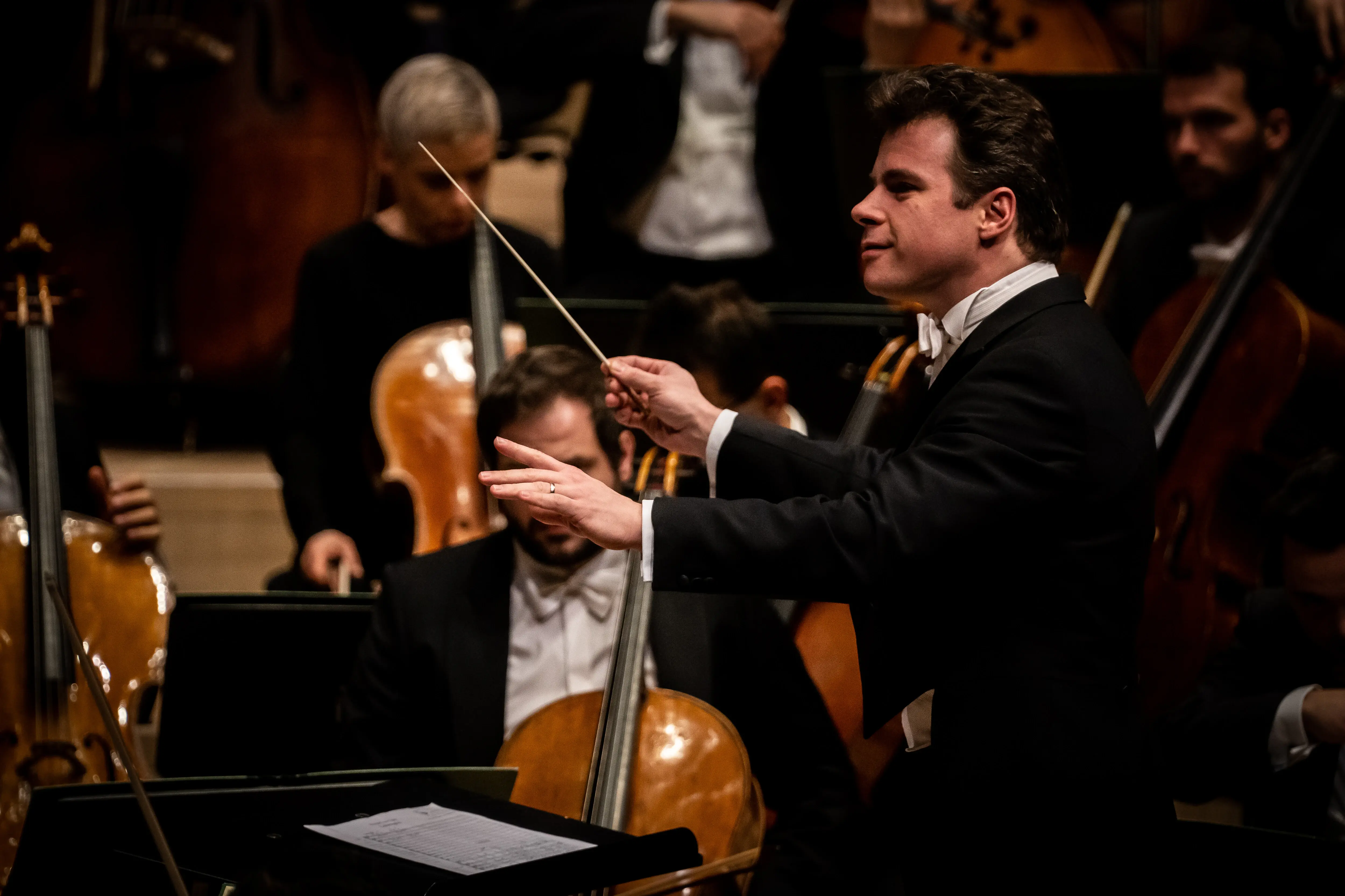 Jakub Hrůša Ein Mann dirigiert ein Orchester mit Streichinstrumenten.