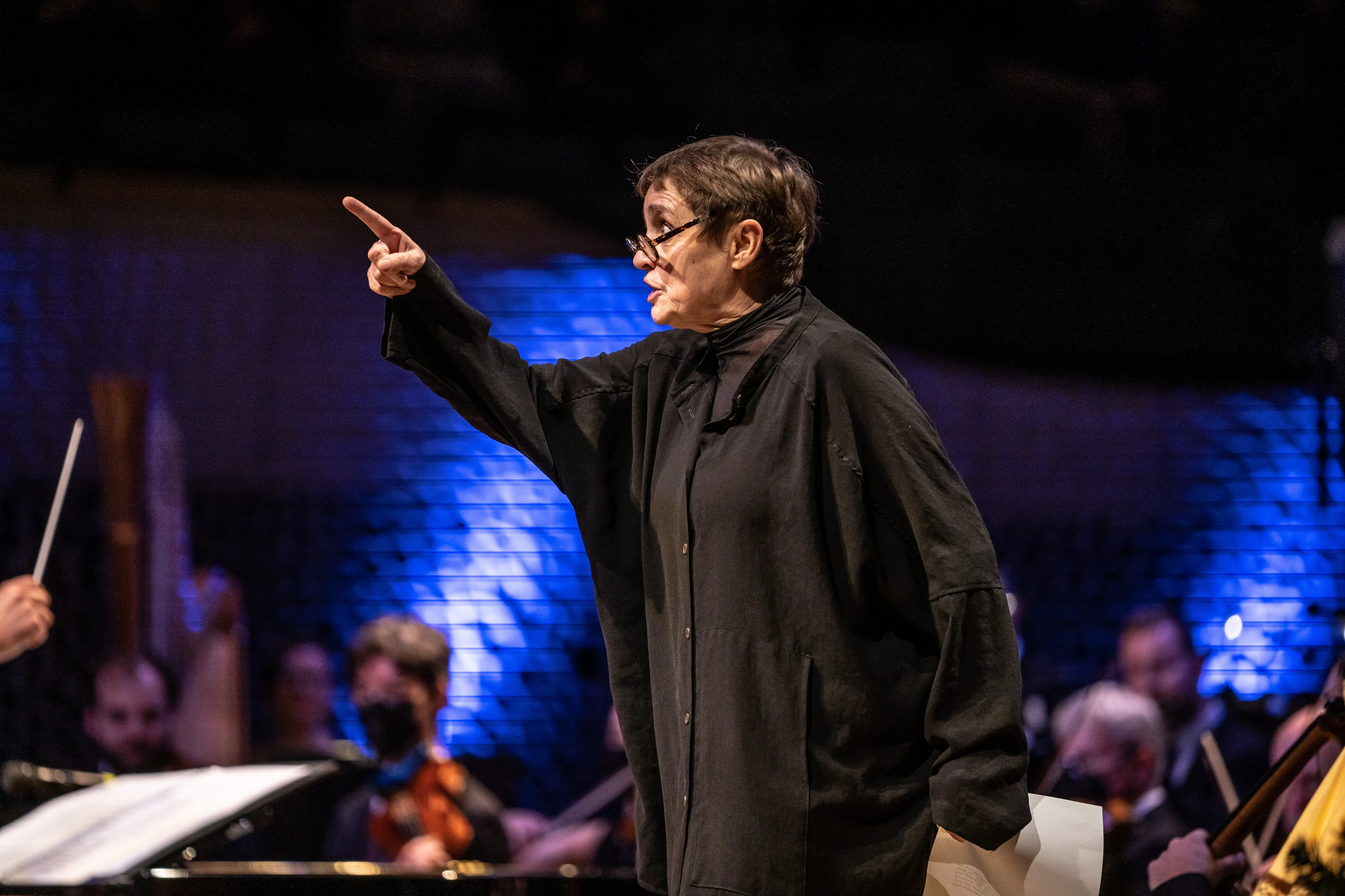 A woman in glasses pointing at something.