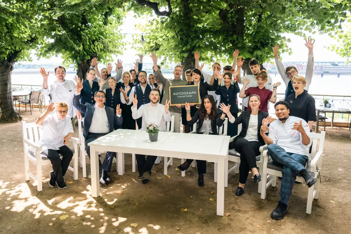 Das Hotel- und Service-Team des Hotels Louis C. Jacob sitzt und steht versammelt auf der Lindenterrasse.