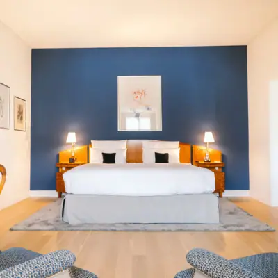 Ein Zimmer im Hotel Louis C. Jacob mit einem Bett vor einer blauen Wand.