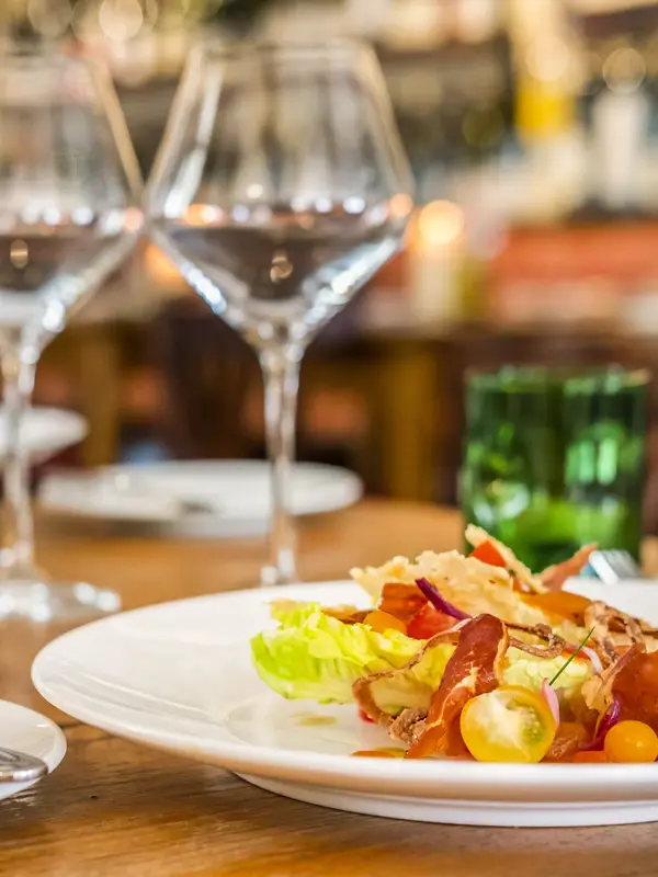 A plate of food with a wine glass on a table.
