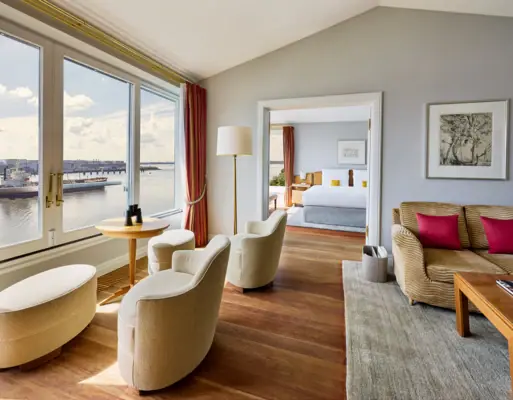 A room with a view of the water and a bed in the foreground.